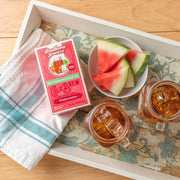 Southern Breeze Decaf Watermelon Sweet Iced Tea on a tray with two iced tea jars and watermelon slices in a bowl