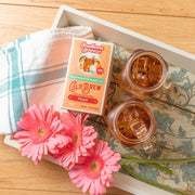 Southern Breeze Decaf Peach Sweet Iced Tea on a tray with two iced tea jars and flowers