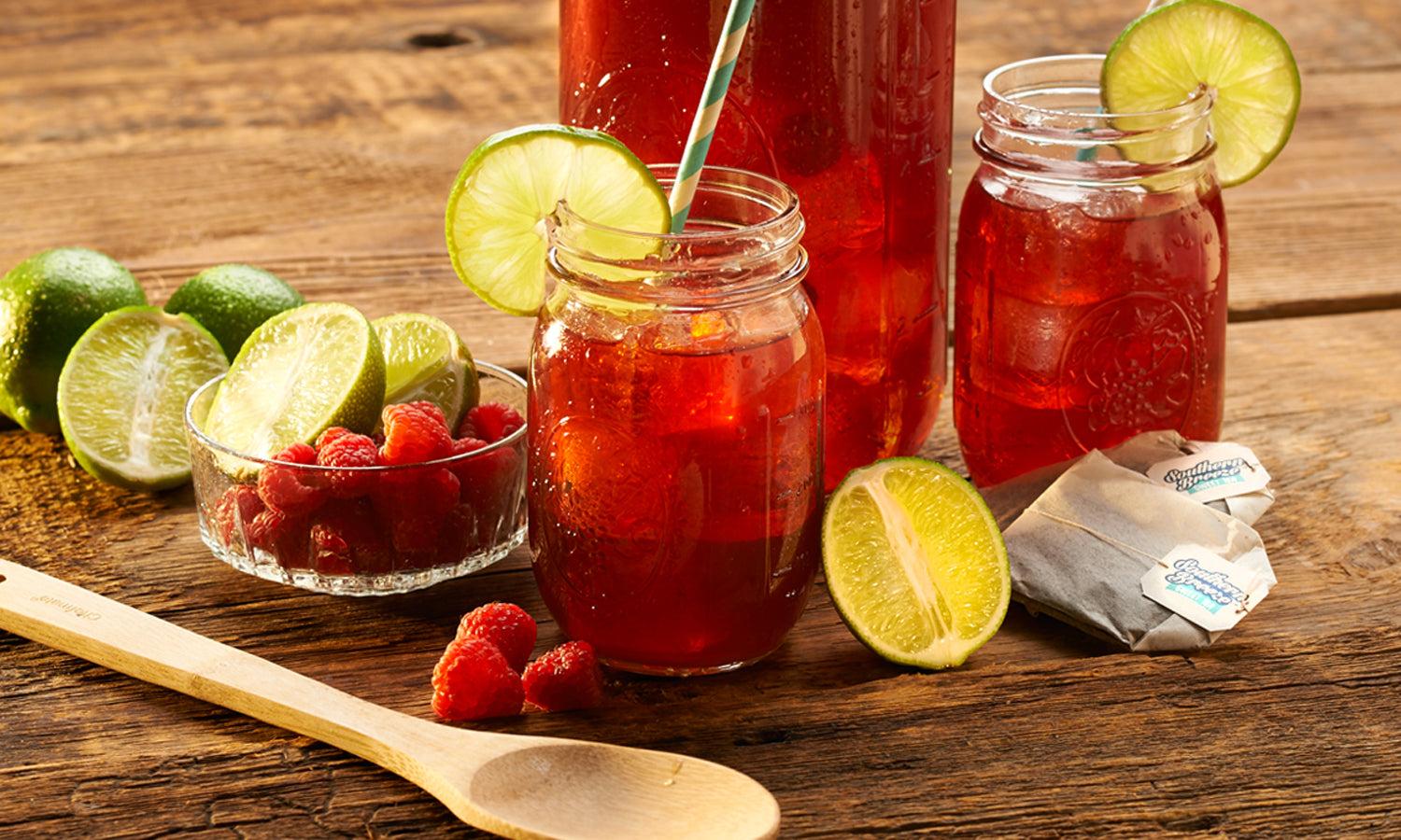 Raspberry Ginger Lime Sweet Tea kept on a table alongside slices of lemon and spoon