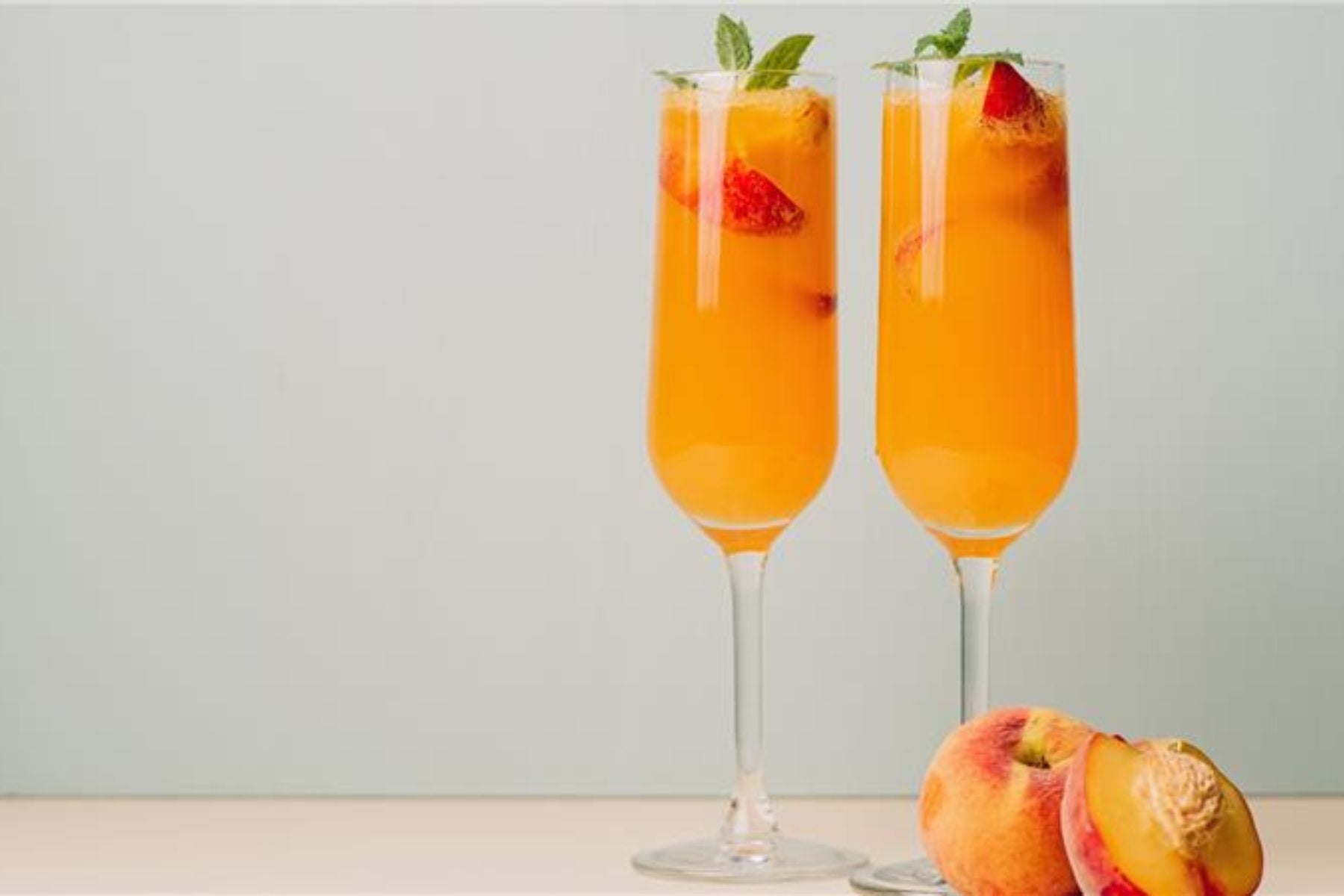 Close up shot of Peach Sweet Tea Mimosa with Peach on the side