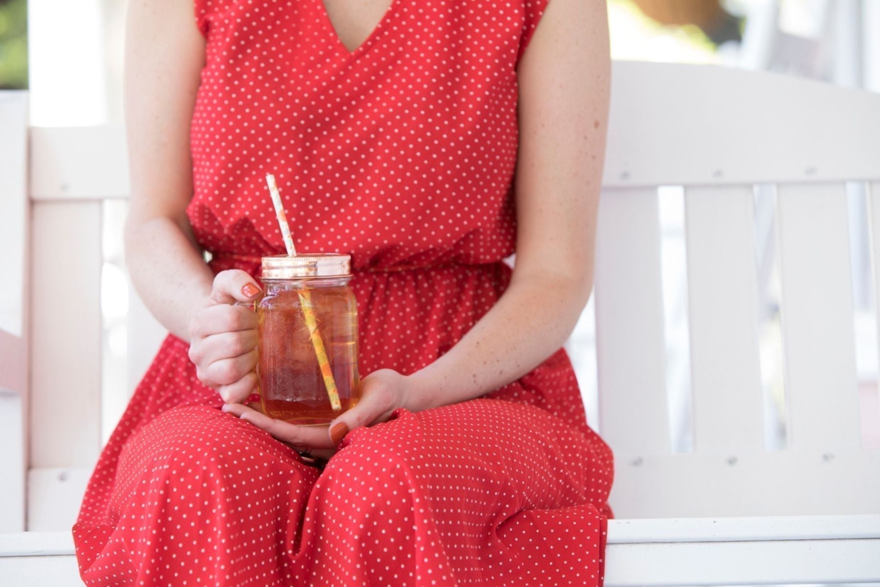 A person holding a mason jar full of iced tea