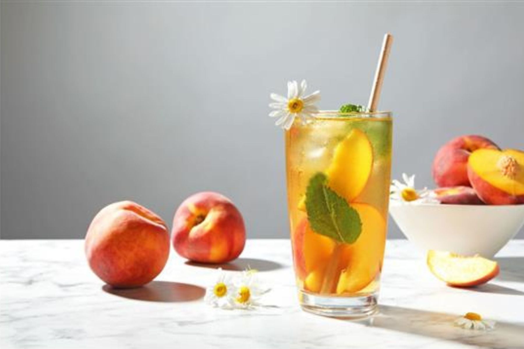 Peach tea alongside several peaches