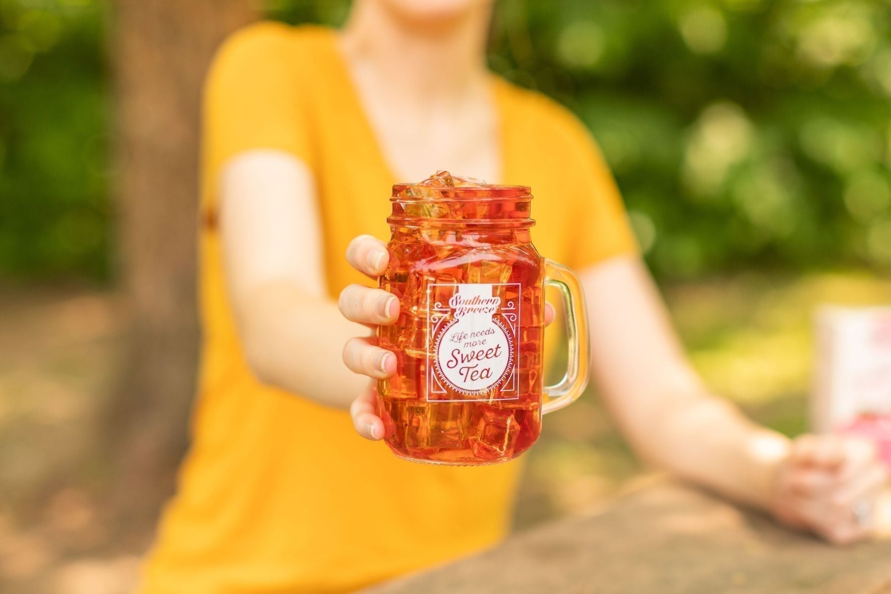 A person holding a mason jar full of iced tea