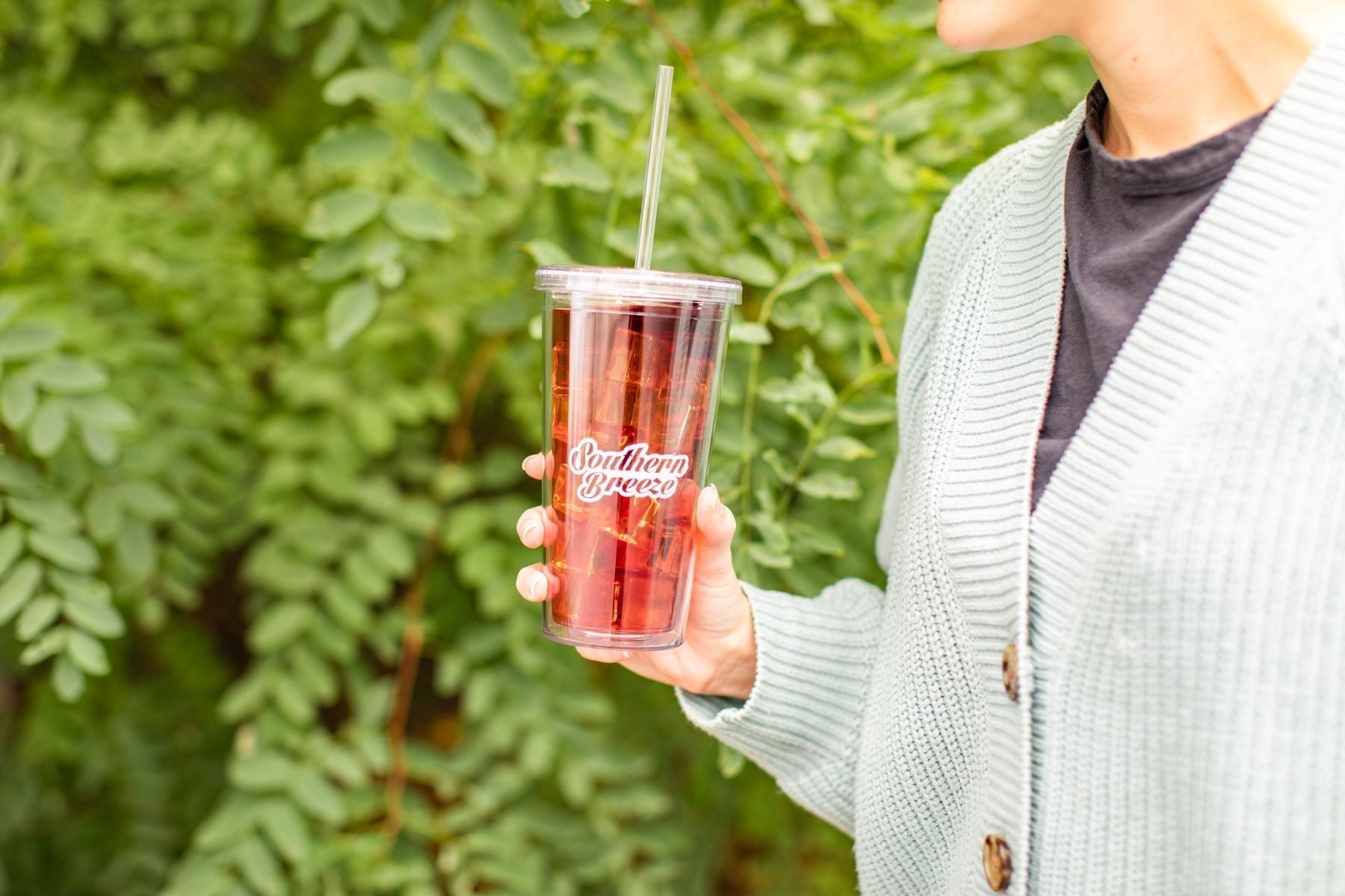 A person holding a glass filled with Iced Tea