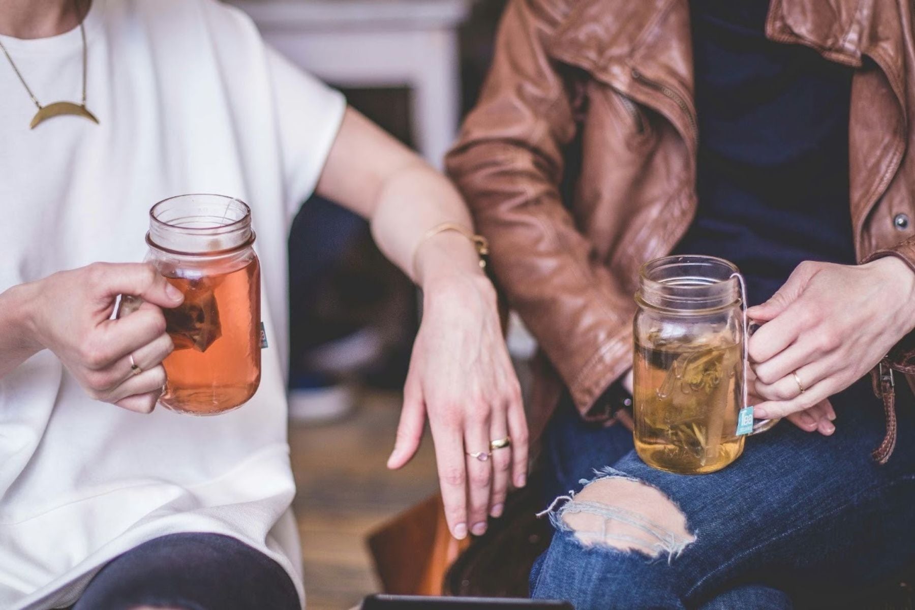 Two people holding mason jars of iced tea while sitting together