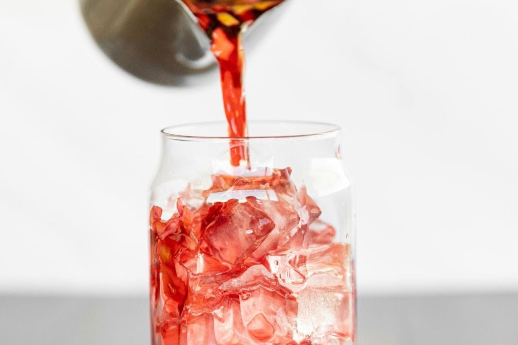 Red iced tea poured over ice in a glass