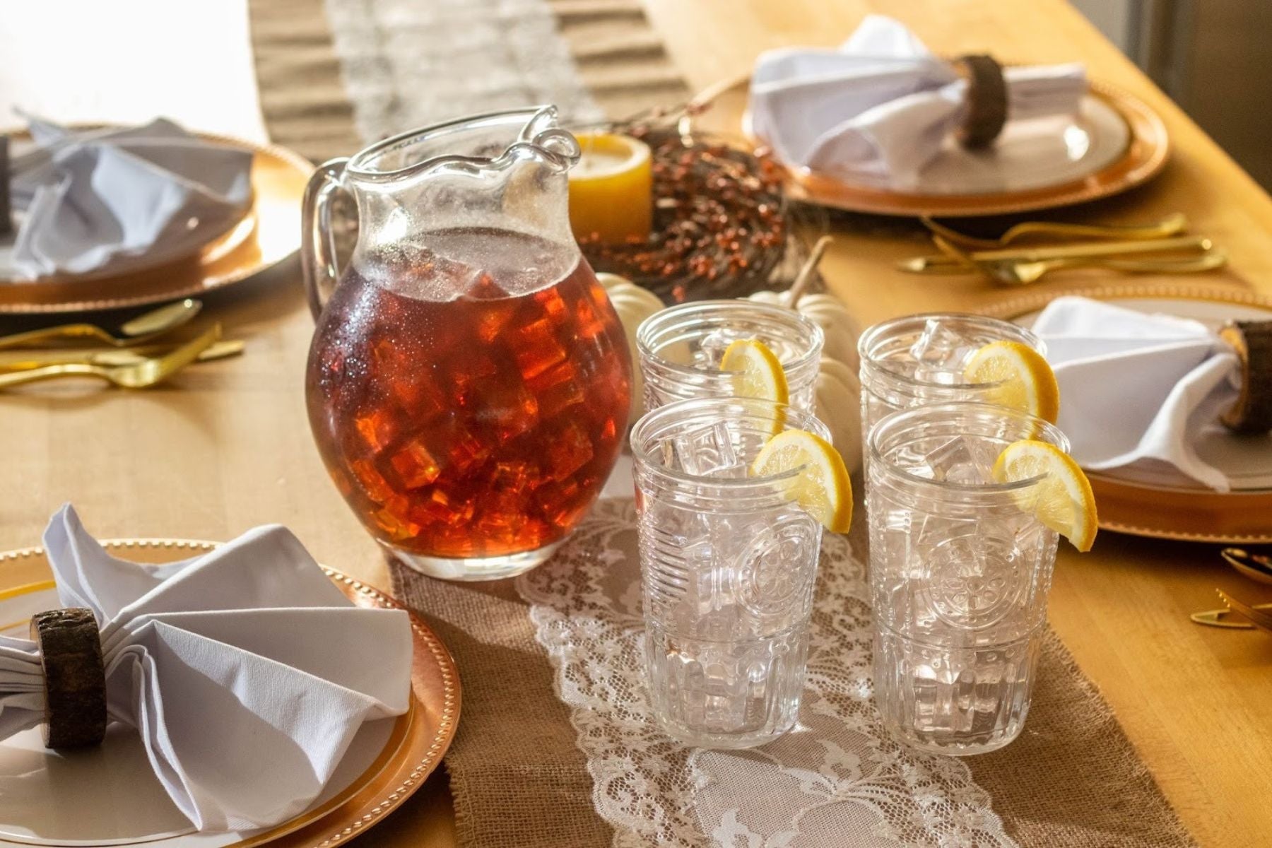 Pitcher of iced tea with lemon slices and glasses set on a dining table