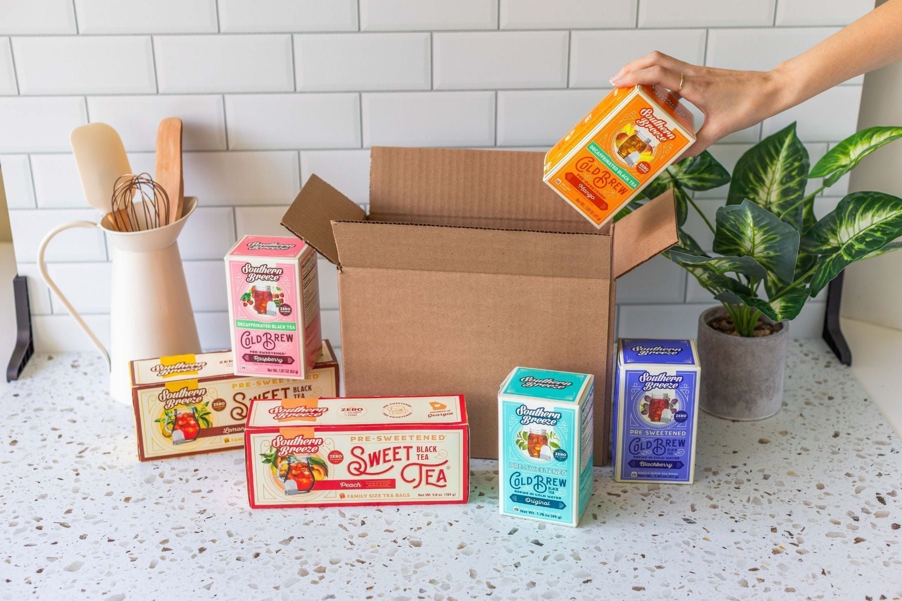 Assorted Southern Breeze sweet tea and cold brew tea boxes arranged around an open shipping box on a kitchen counter
