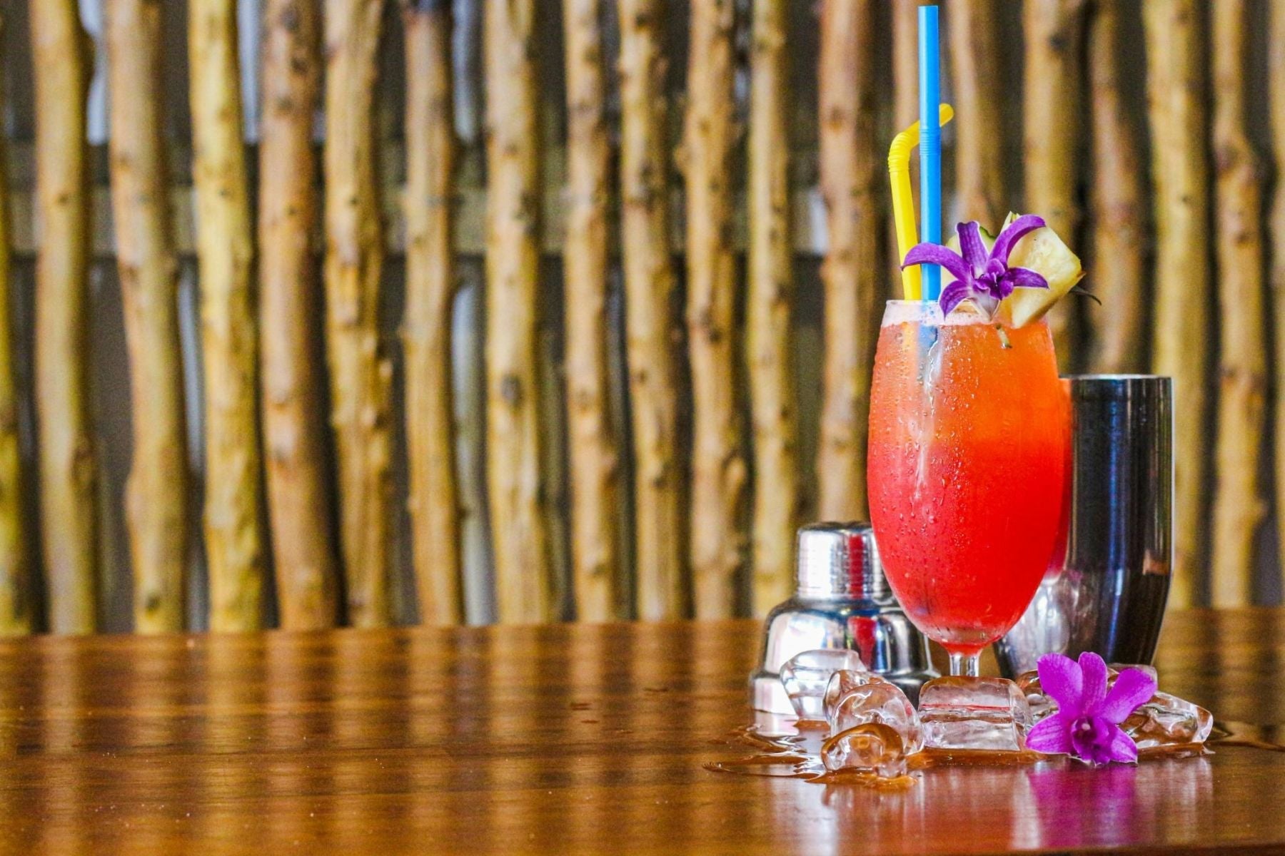Cherry Lime Sweet Tea Mocktail  with layered colors, pineapple garnish, and orchid flower served on a bar counter