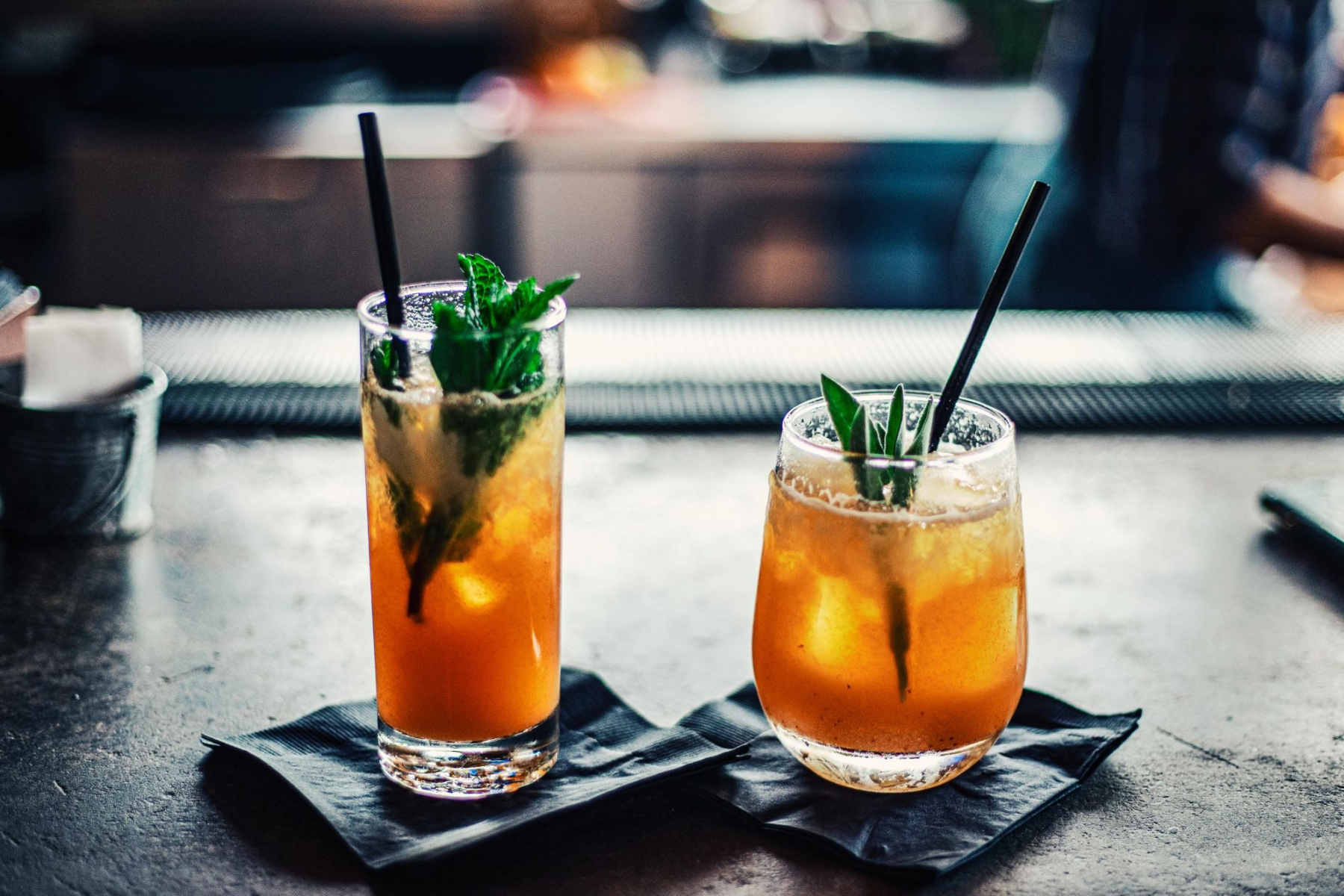 Two Basil Lime Sweet Tea Mocktail with served in tall and short glasses on a bar counter