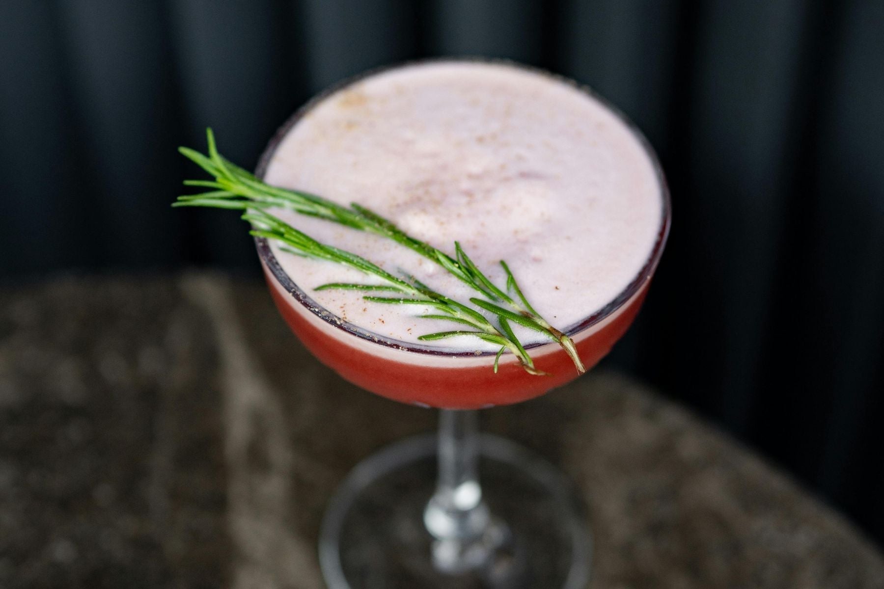Blackberry Mimosa with foam and a rosemary garnish.