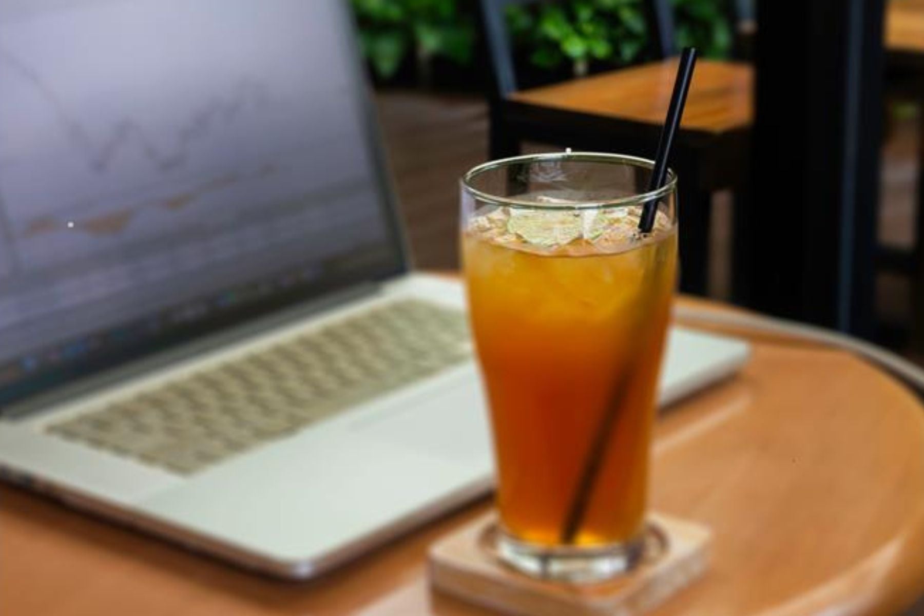 A glass of decaf sweet tea alongside a laptop