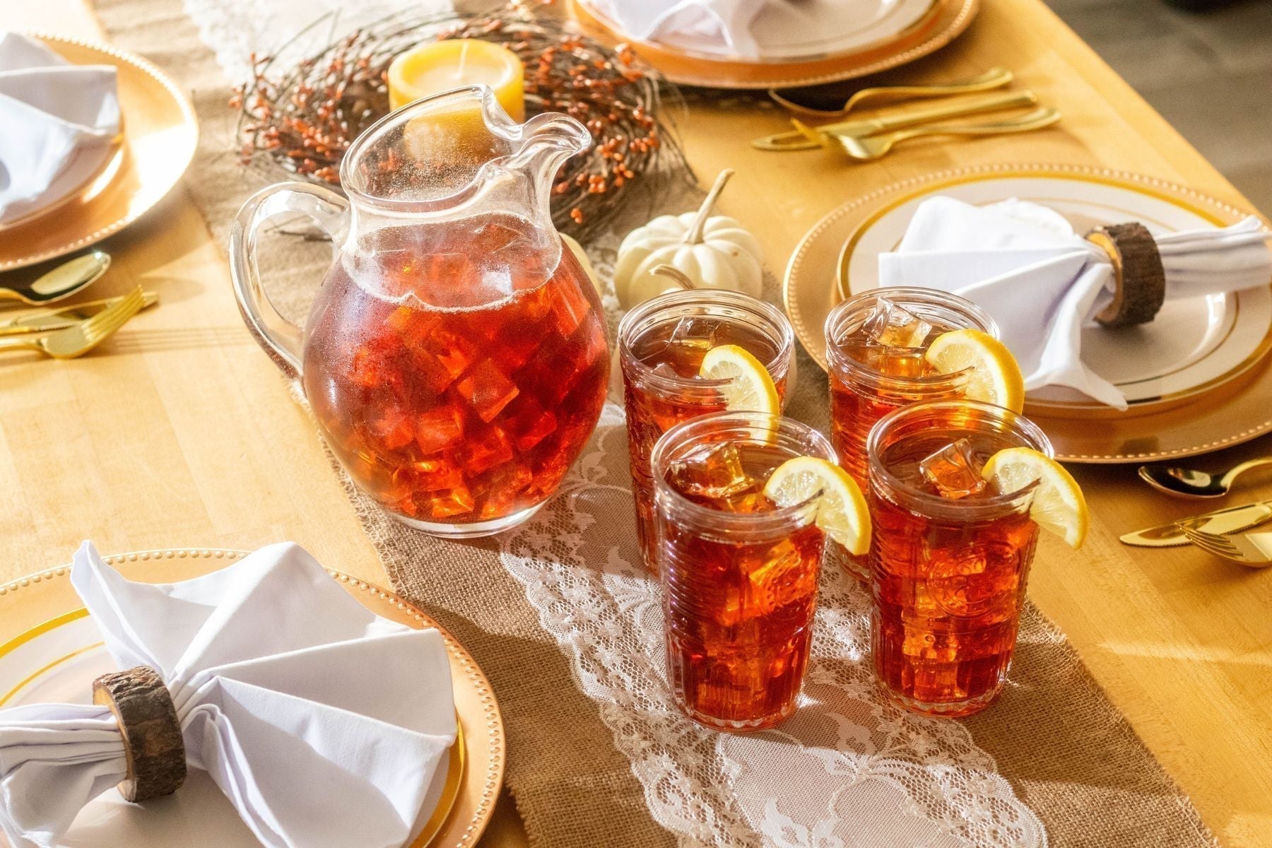 Iced tea pitcher and glasses set on a table.