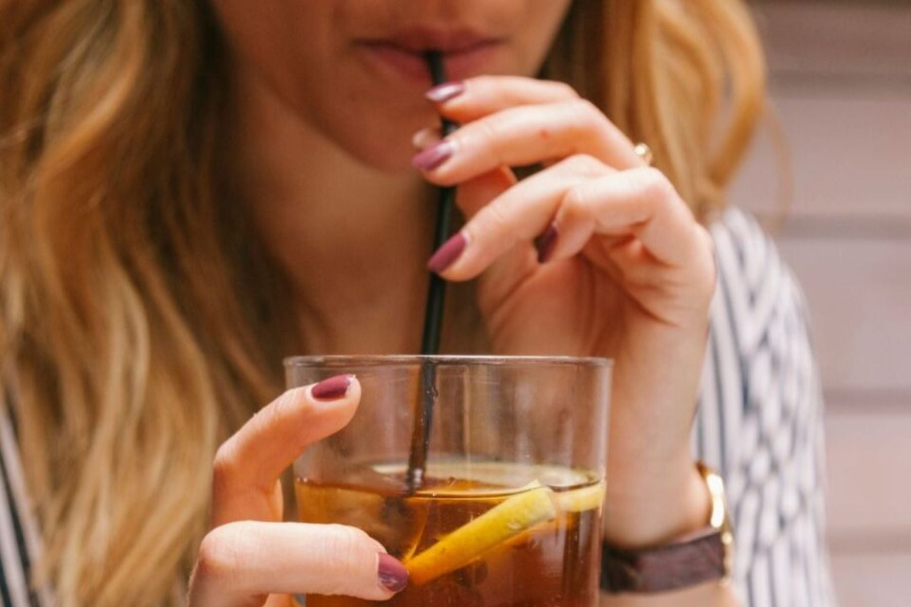 A person drinking iced tea with a straw