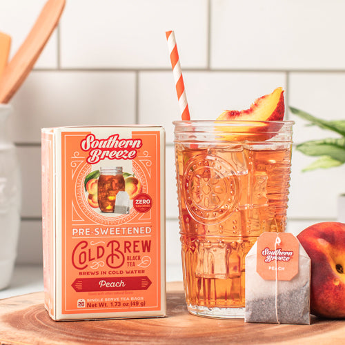 Southern Breeze peach iced tea packaging with a glass of tea and peach slices on a wooden surface.