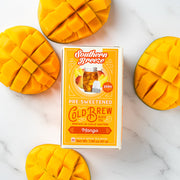 Box of Southern Breeze Mango Cold Brew tea with sliced mangoes on a marble background