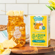 Mason jar filled with a sweet tea drink and a box of Southern Breeze pre-sweetened cold brew tea on a wooden surface.