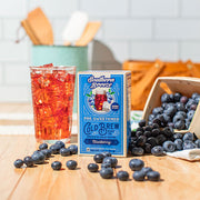 Southern Breeze pre-sweetened cold brew black tea bags with blueberries and a glass of iced tea on a wooden table.