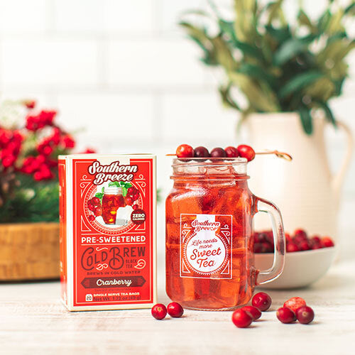 Southern Breeze Sweet Tea package with a glass of tea and cranberries on a table.