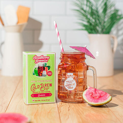 Southern Breeze pre-sweetened cold brew box with a glass of iced tea and guava on a wooden table.