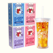 Four Southern Breeze Cold Brew tea boxes in blue, pink, and purple flavors  - Blackberry, Raspberry, Strawberry & Blueberry flavor - arranged next to a clear plastic tumbler with a straw filled with iced tea, on a light cream background.